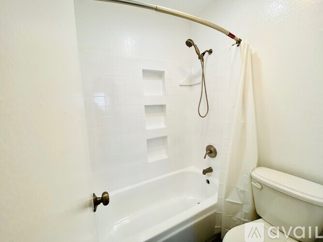 A white bathroom with a tub, shower, and toilet.