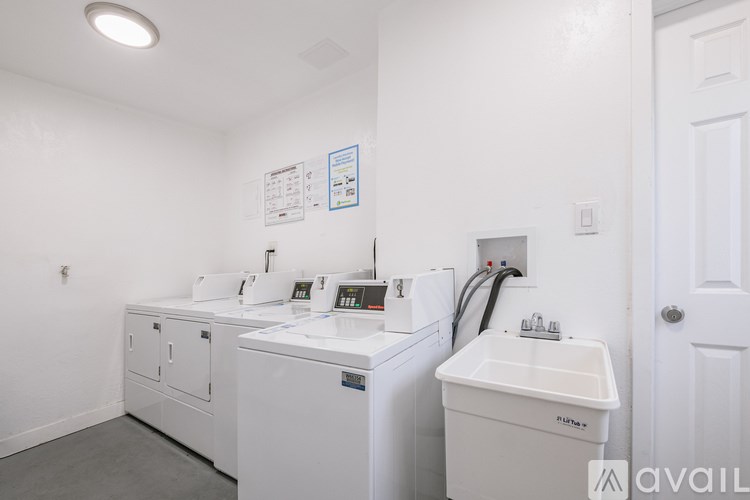 A white bathroom with a white sink and a white washer and dryer.