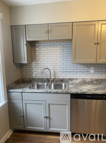 A kitchen with a stainless steel dishwasher and a marble countertop.