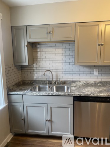 A kitchen with a stainless steel dishwasher and a marble countertop.