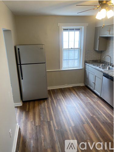 A kitchen with a refrigerator and wooden floors.