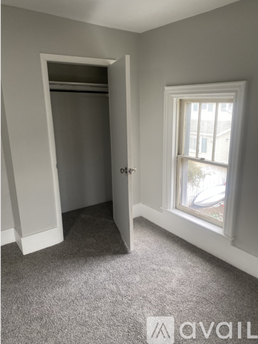 A room with a carpeted floor, a door, and a window.