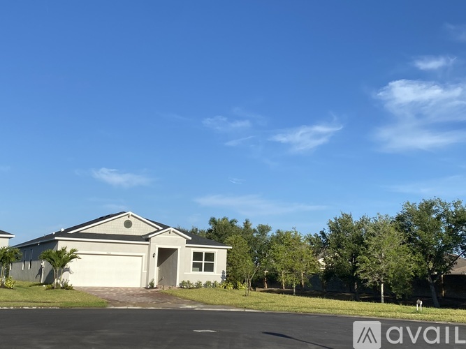 A house with a garage and a tree in front of it.