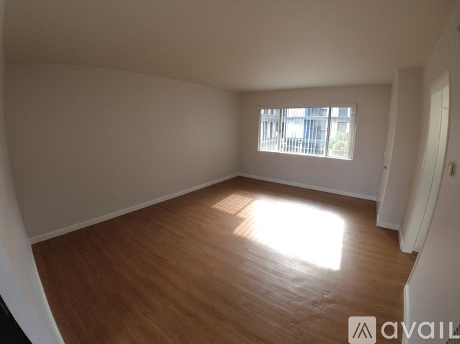 A room with wooden flooring and a window letting in sunlight.