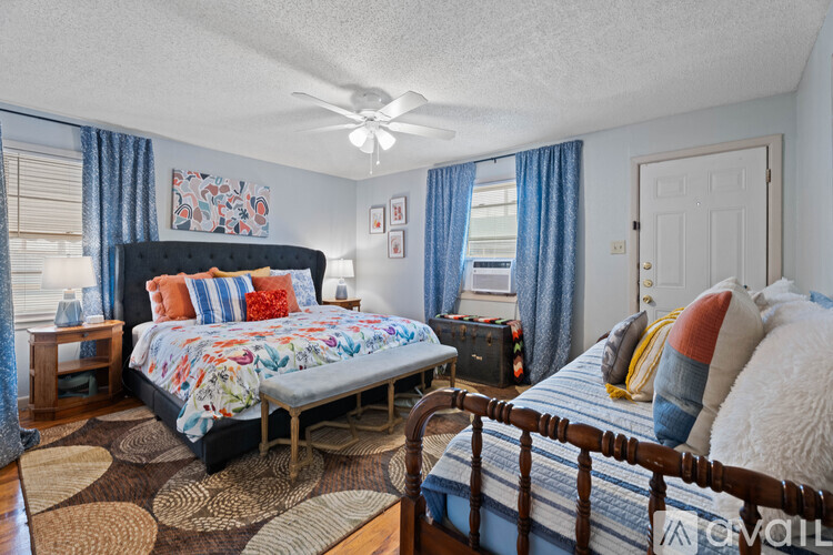 A bedroom with a bed, a nightstand, and a fan.