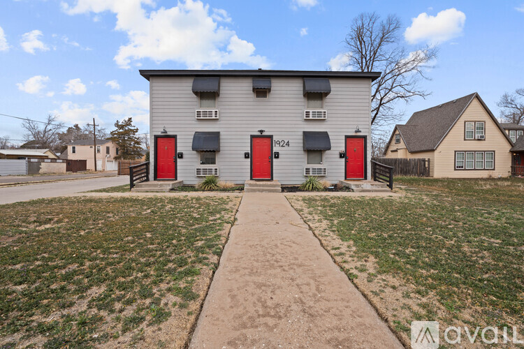 A two-story building with red doors and a sidewalk in front.