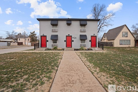 A two-story building with red doors and a sidewalk in front.