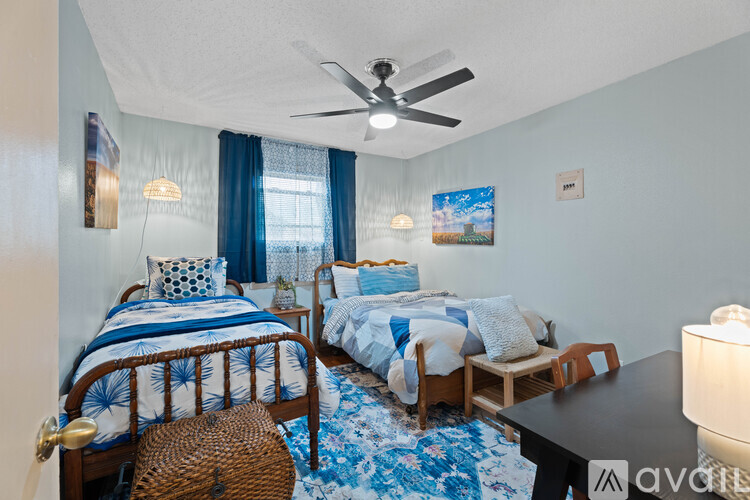 A bedroom with two beds and a ceiling fan.