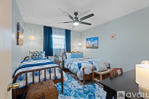 A bedroom with two beds and a ceiling fan.