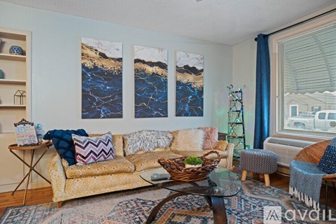 A living room with a couch, a table, and a painting on the wall.