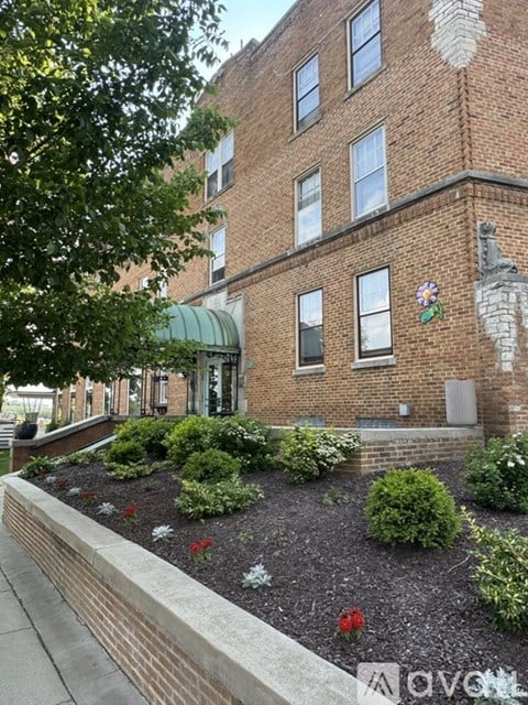 A brick building with a green awning and a flower in the window.