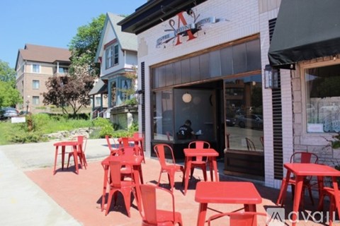 A restaurant with red chairs and tables outside.