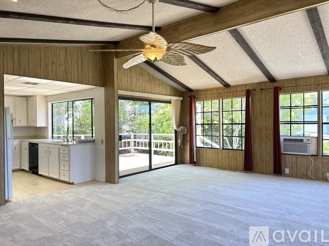 A spacious room with a ceiling fan and large windows.