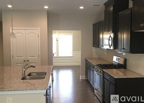 A kitchen with black cabinets and a granite countertop.