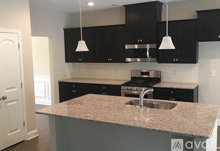 A kitchen with granite countertops and black cabinets.