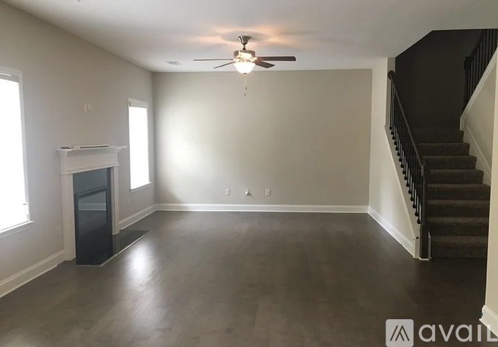 A spacious room with a staircase and a fireplace.