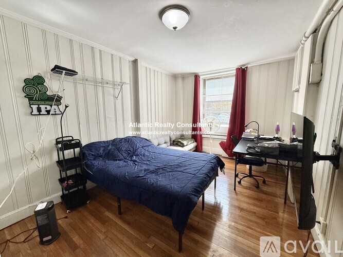A bedroom with a bed, nightstand, and a window with a view of the city.
