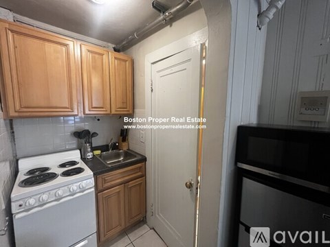A kitchen with wooden cabinets and a white stove top oven.