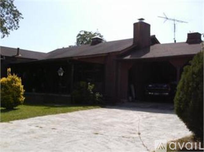 A house with a brick chimney and a car in the driveway.