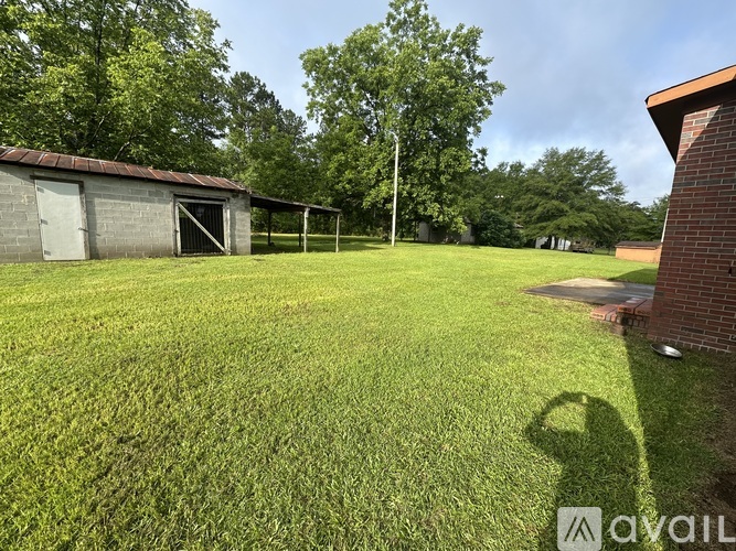 A grassy field with a building and trees in the background.