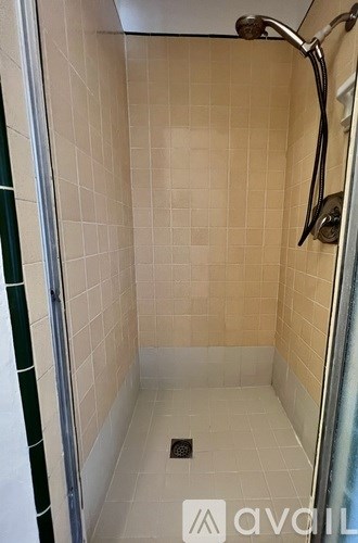 A shower area with a glass door and a drain in the middle.