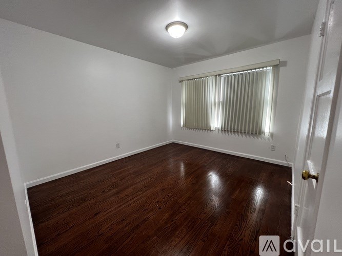 A room with wooden flooring and a window with blinds.