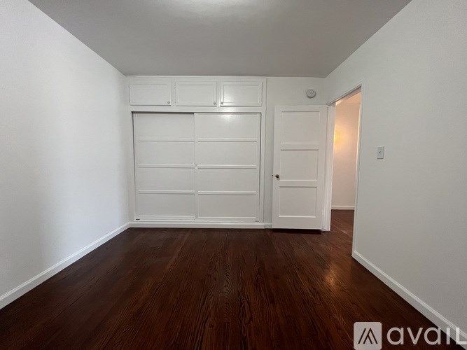 A room with a white door and a wooden floor.