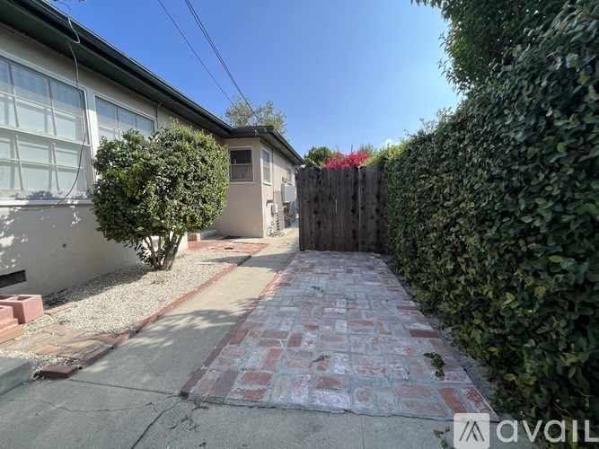 A backyard with a brick pathway leading to a house.