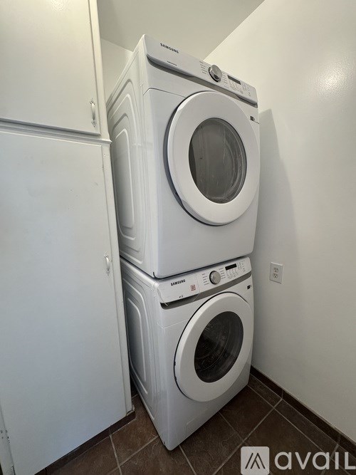 A stack of white front loading washing machines in a laundry room.