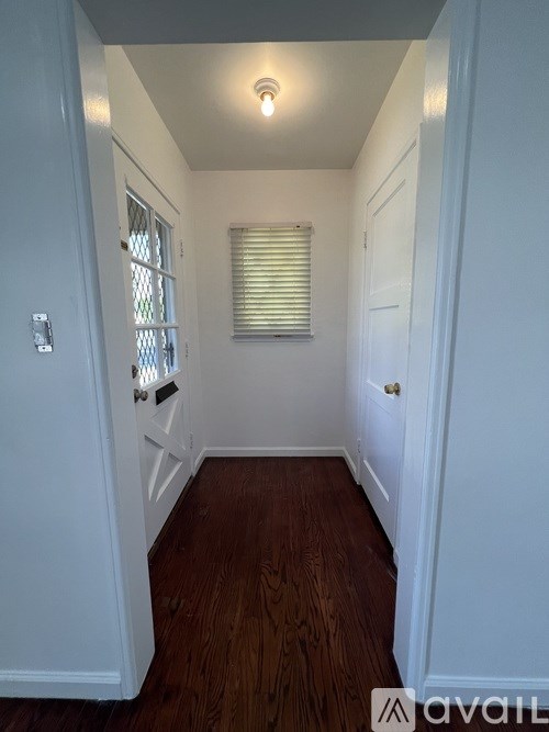 A hallway with a wooden floor and white walls.