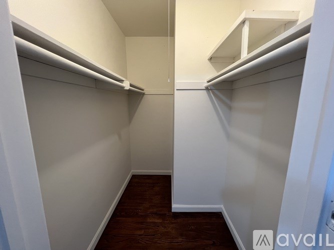 A small, empty closet with white shelves and a wooden floor.