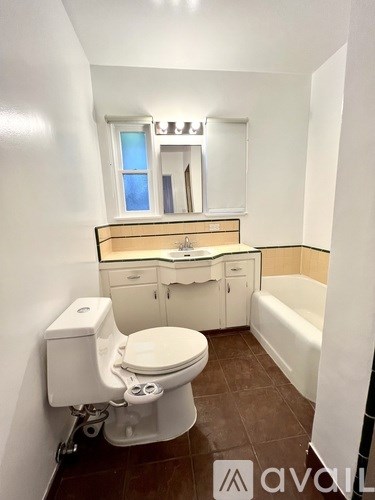 A small white toilet with a tank and a toilet paper holder is in a small bathroom.