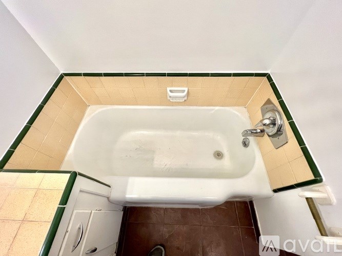 A white bathtub with a green border is in a bathroom.