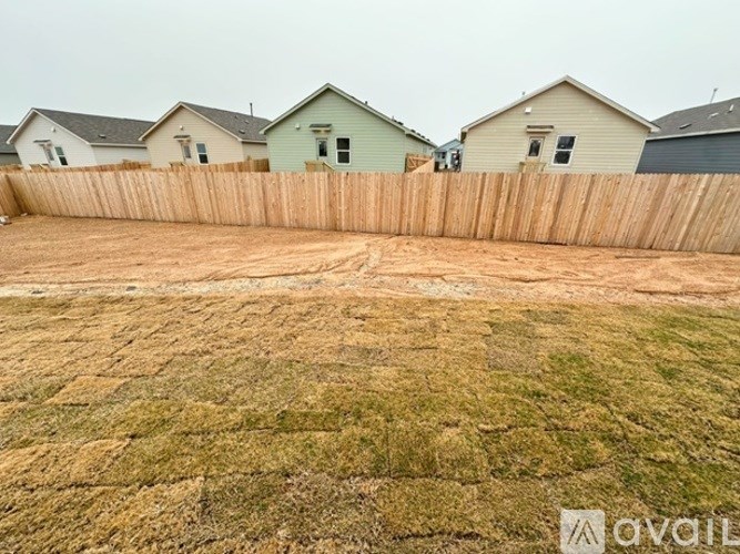 A backyard with a wooden fence and a grassy area in front.