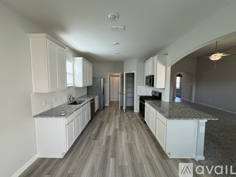 A spacious kitchen with white cabinets and a granite countertop.