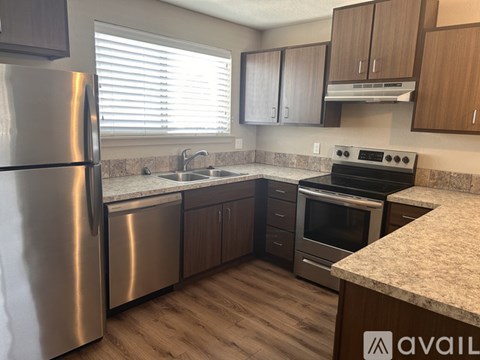 A kitchen with a stainless steel refrigerator and wooden cabinets.
