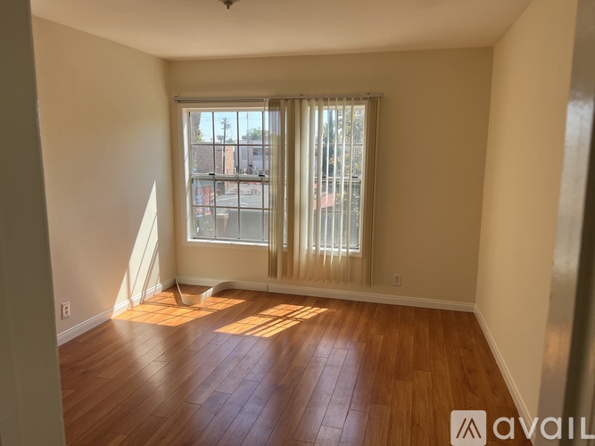 A room with wooden floors and a window with blinds.