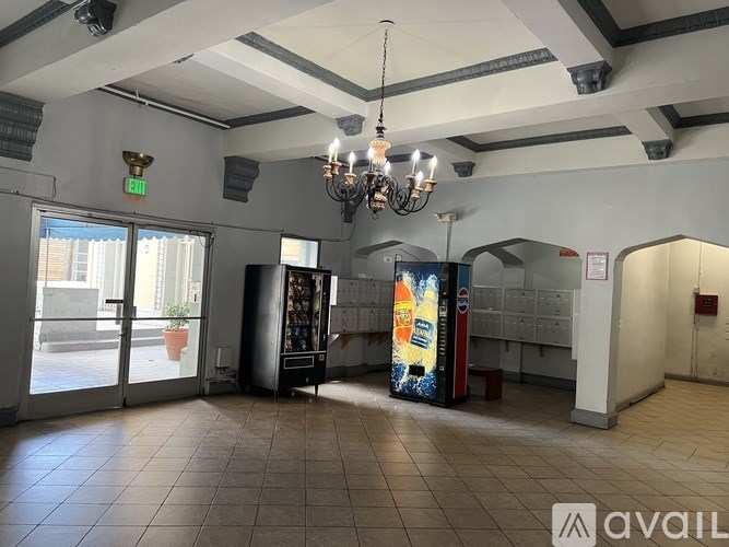 A room with a chandelier, a fridge, and a vending machine.