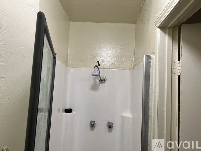 A white shower stall with a glass door and a shower head.
