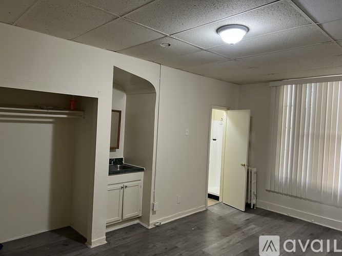 A room with a kitchenette and a door leading to another room.