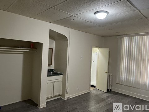 A room with a kitchenette and a door leading to another room.