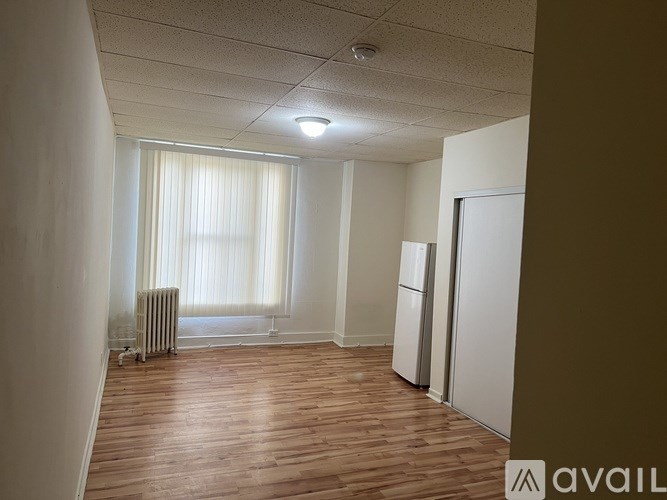 A room with wooden flooring and a window with curtains.