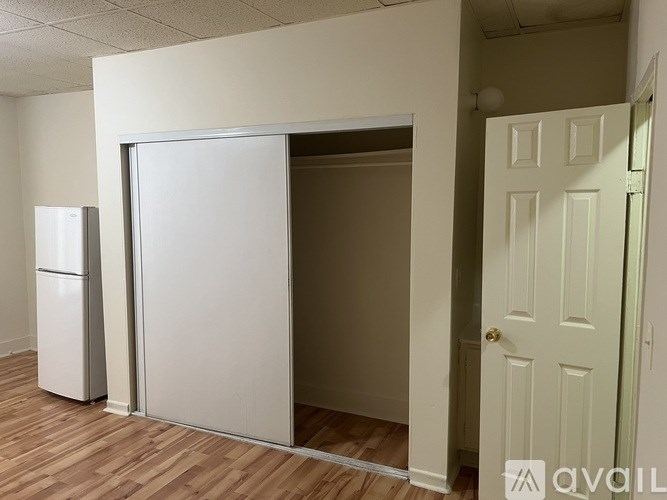 A white refrigerator is next to a white door in a room.