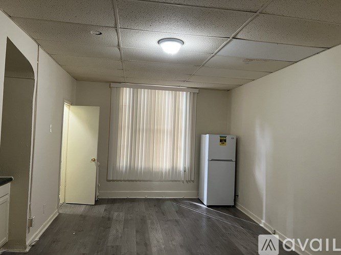 A room with a white fridge and a door with a window.