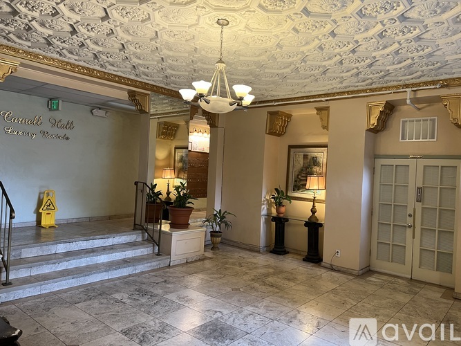 The image shows the interior of a hotel lobby with a staircase on the left and a door on the right.