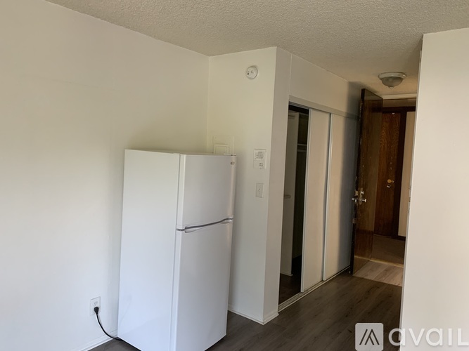 A white refrigerator in a room with a wooden floor.