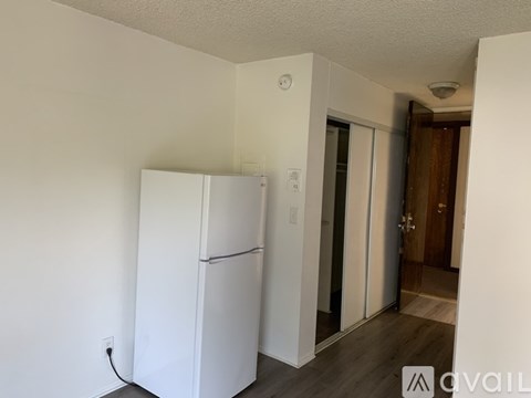 A white refrigerator in a room with a wooden floor.