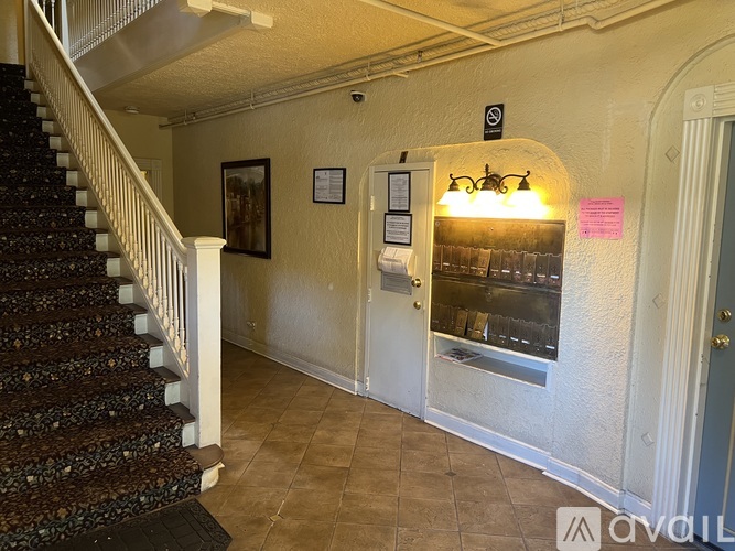 A hallway with a staircase and a bulletin board on the wall.
