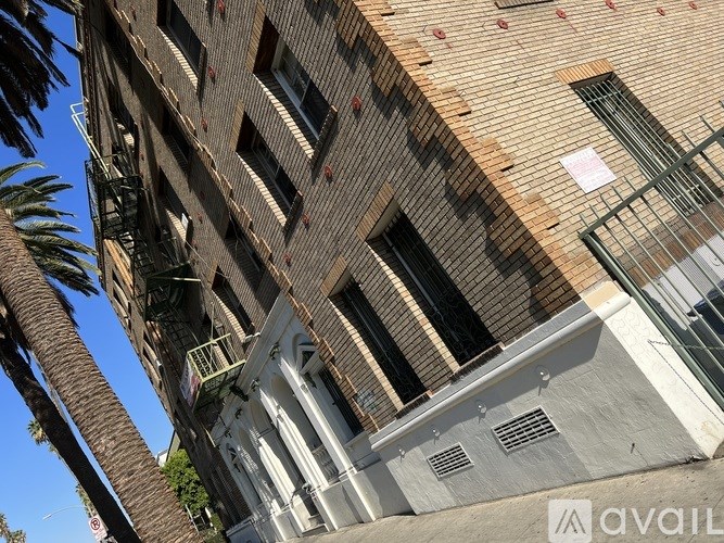 A tall building with a balcony and a palm tree in front of it.