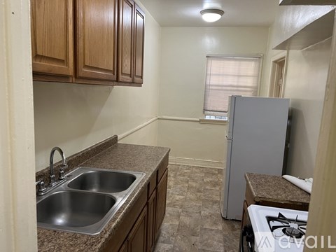 A kitchen with a sink, cabinets, and a refrigerator.